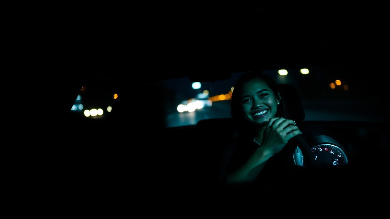 Aluna sorrindo ao volante de um carro de autoescola